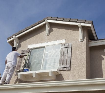 House Painter Painting the Trim And Shutters of Home