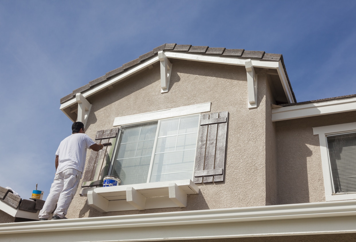 House Painter Painting the Trim And Shutters of Home